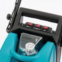 Close-up of a teal and black machine with three red switches and a clear water reservoir.