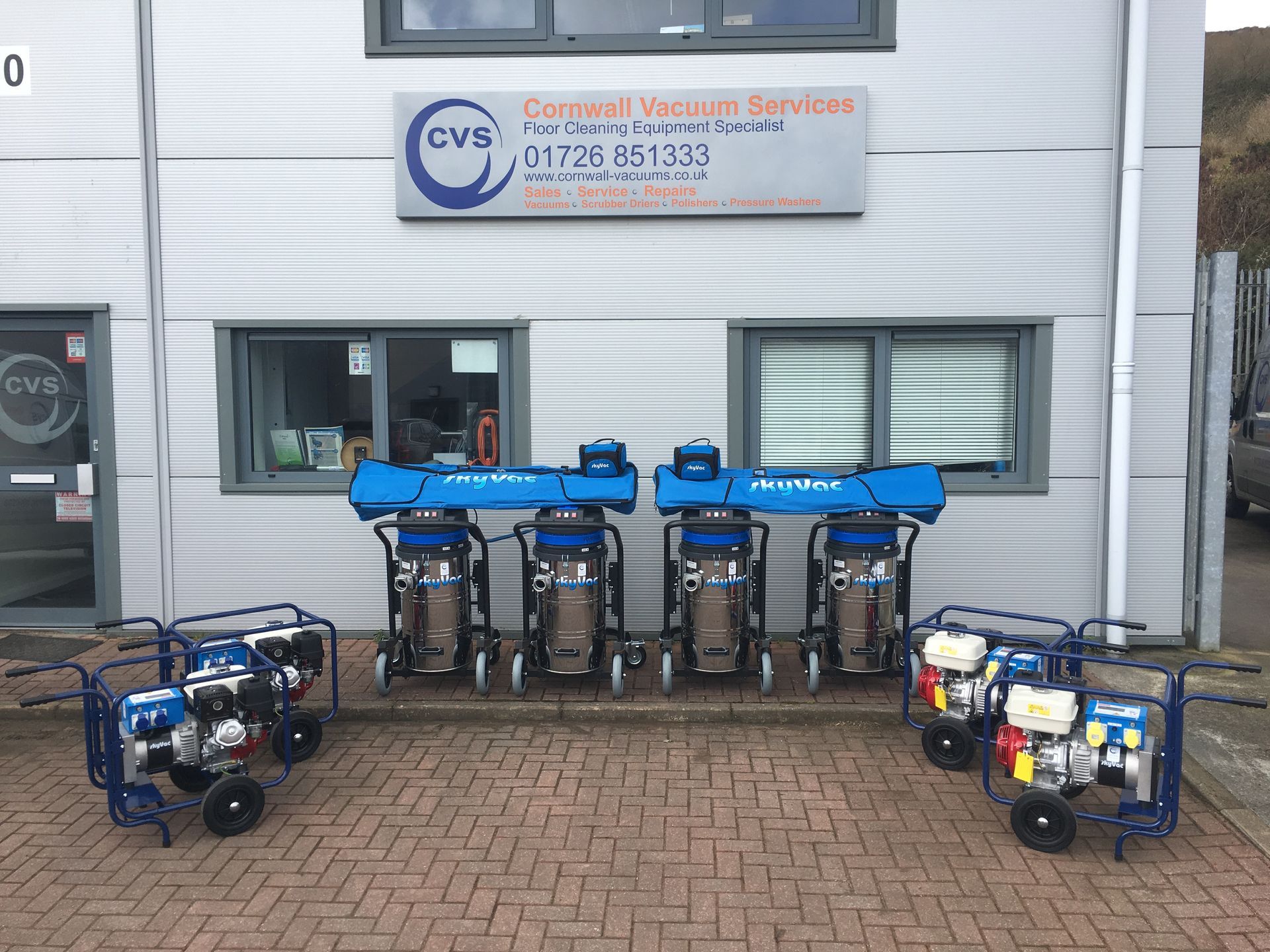 Row of industrial vacuums and generators outside a building with 