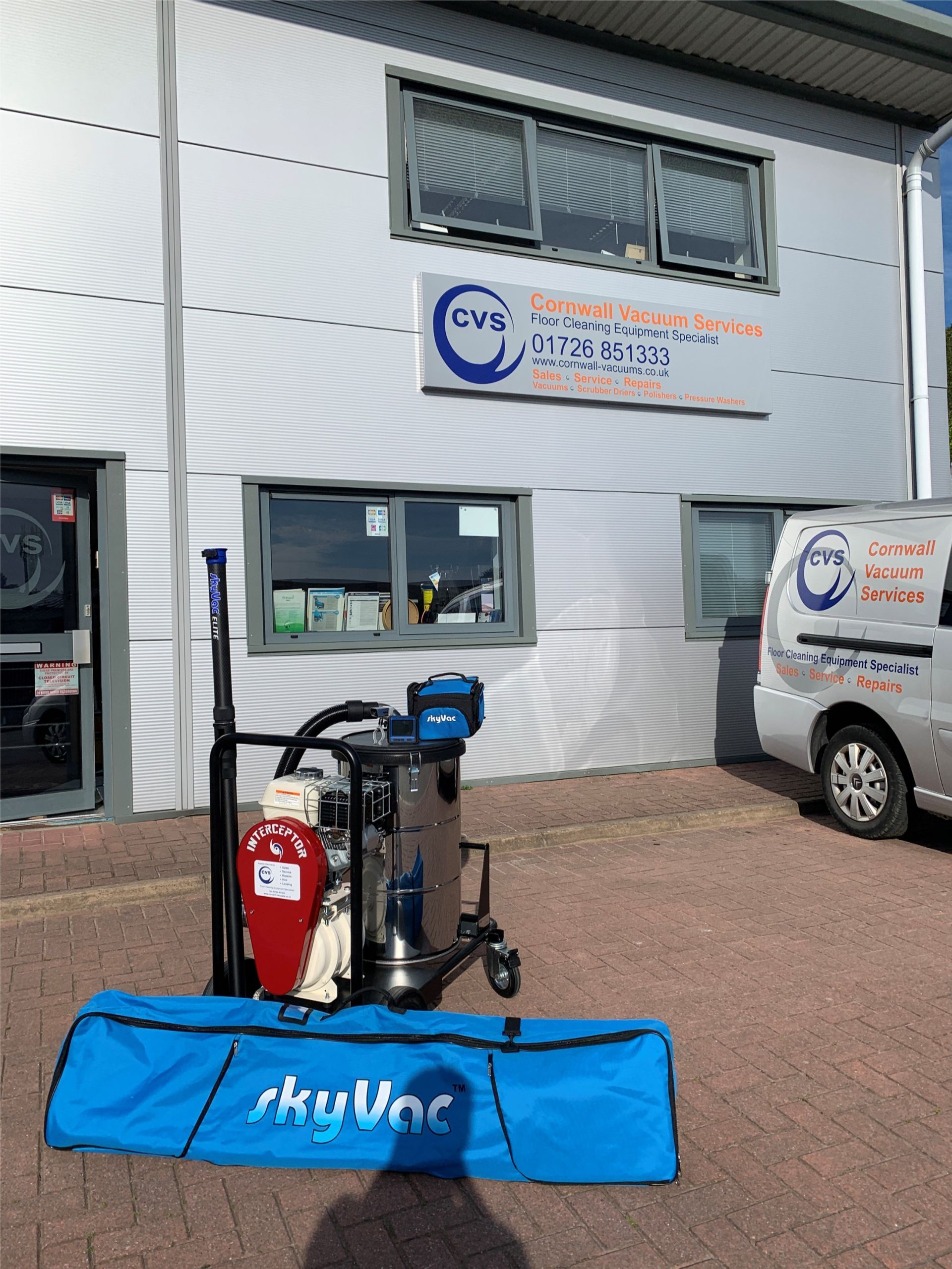 Industrial vacuum cleaner, SkyVac kit, and van parked outside a commercial building.