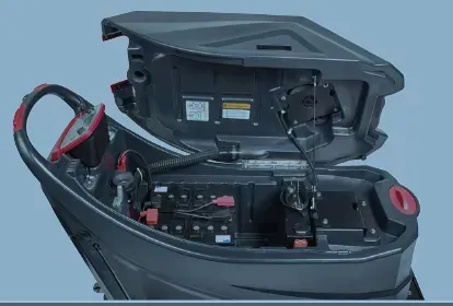Floor cleaning machine in a warehouse. Gray and red machine on concrete floor with boxes in the background.
