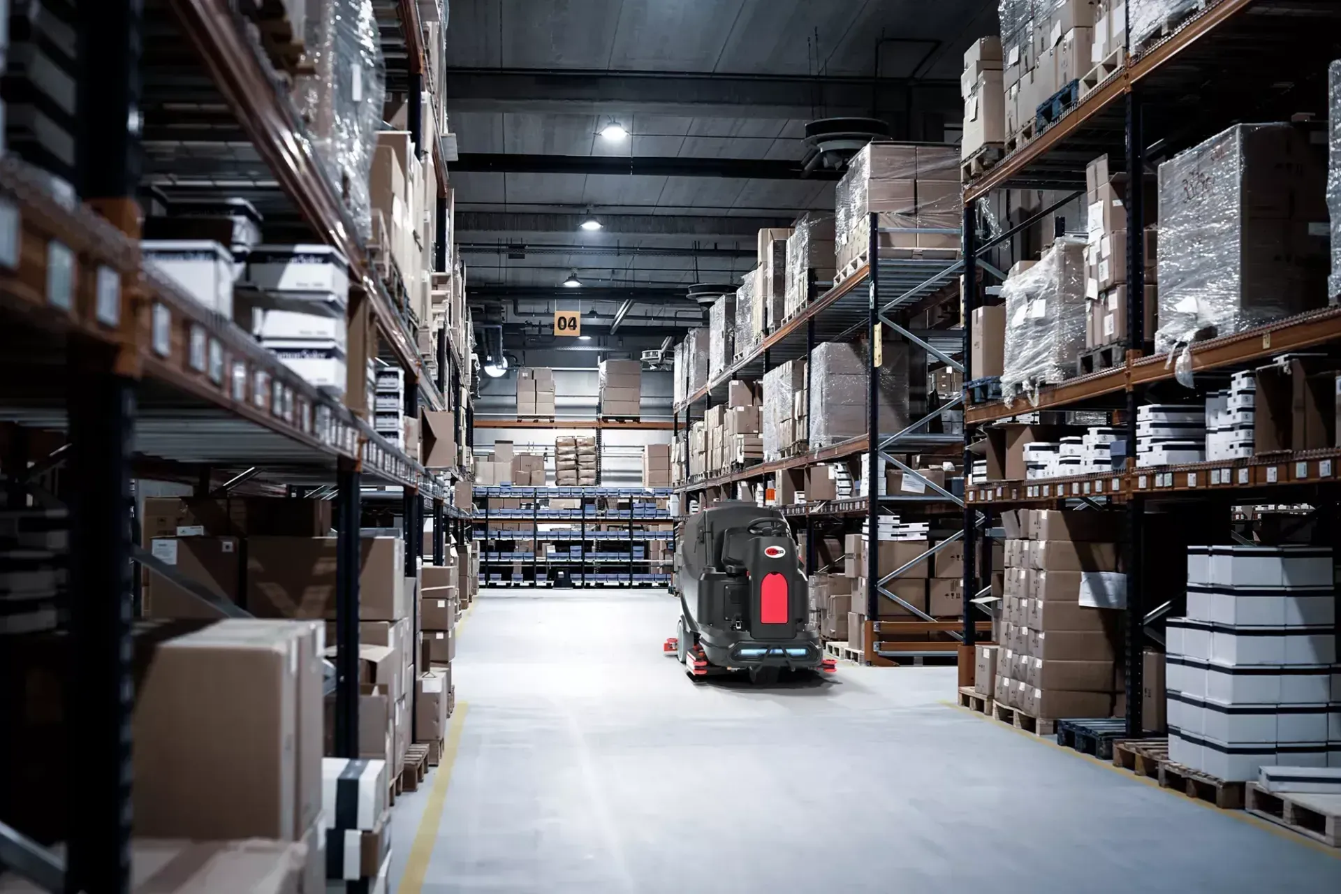 Black and red industrial floor scrubber with steering wheel and flashing light.