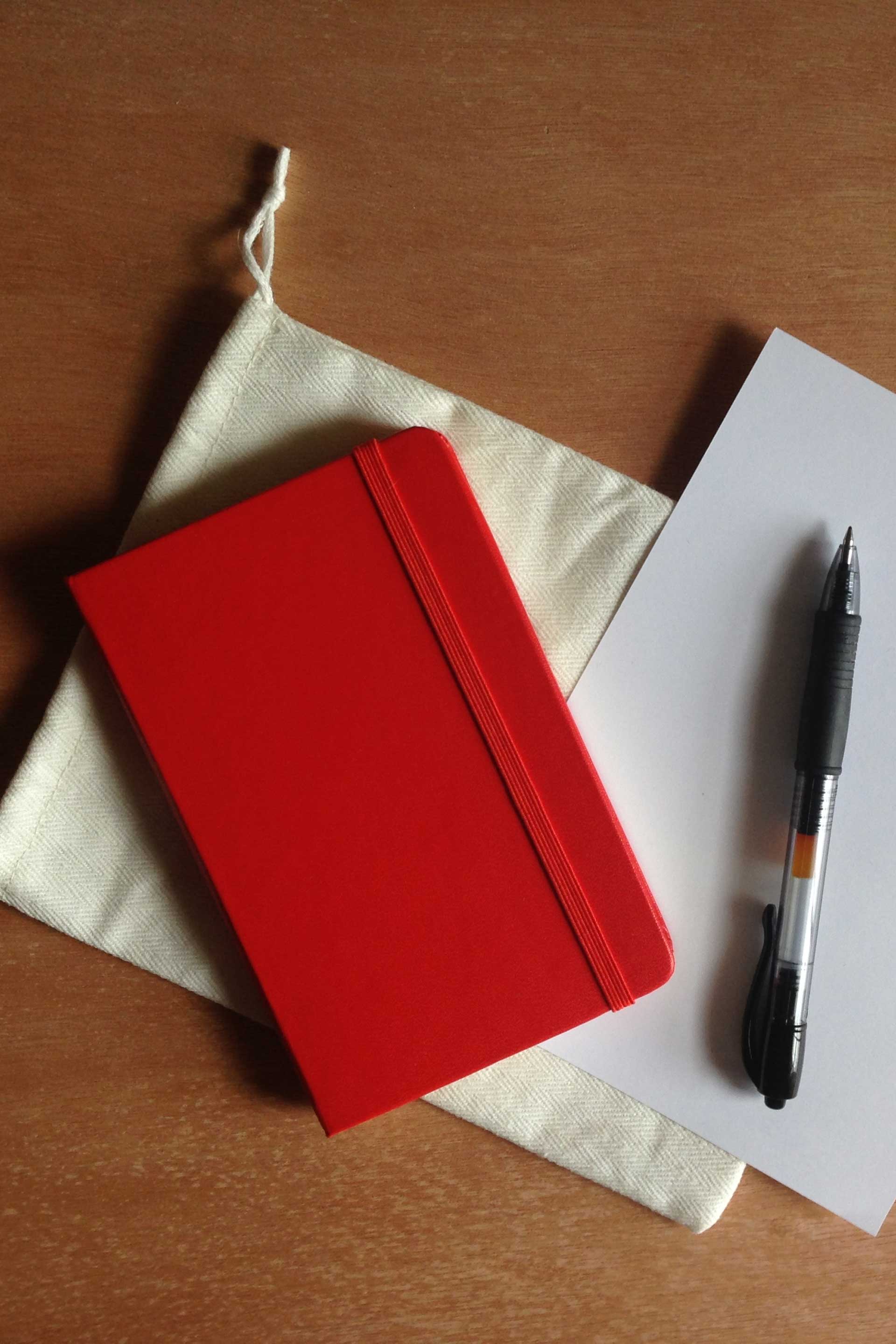 Un taccuino rosso e una penna su un tavolo