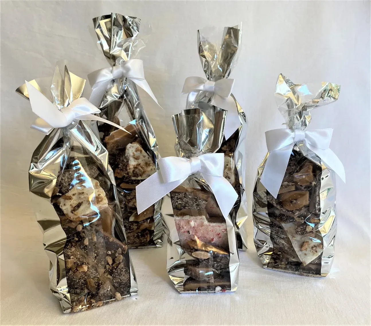 Four bags of candy with bows on them are sitting on a table.