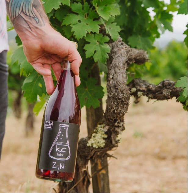 A man is holding a bottle of kc z-n wine