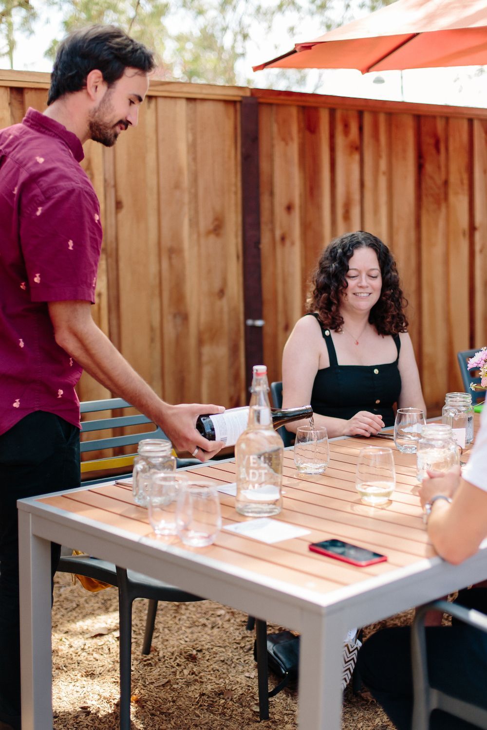 A woman is pouring wine into a glass at a bar.