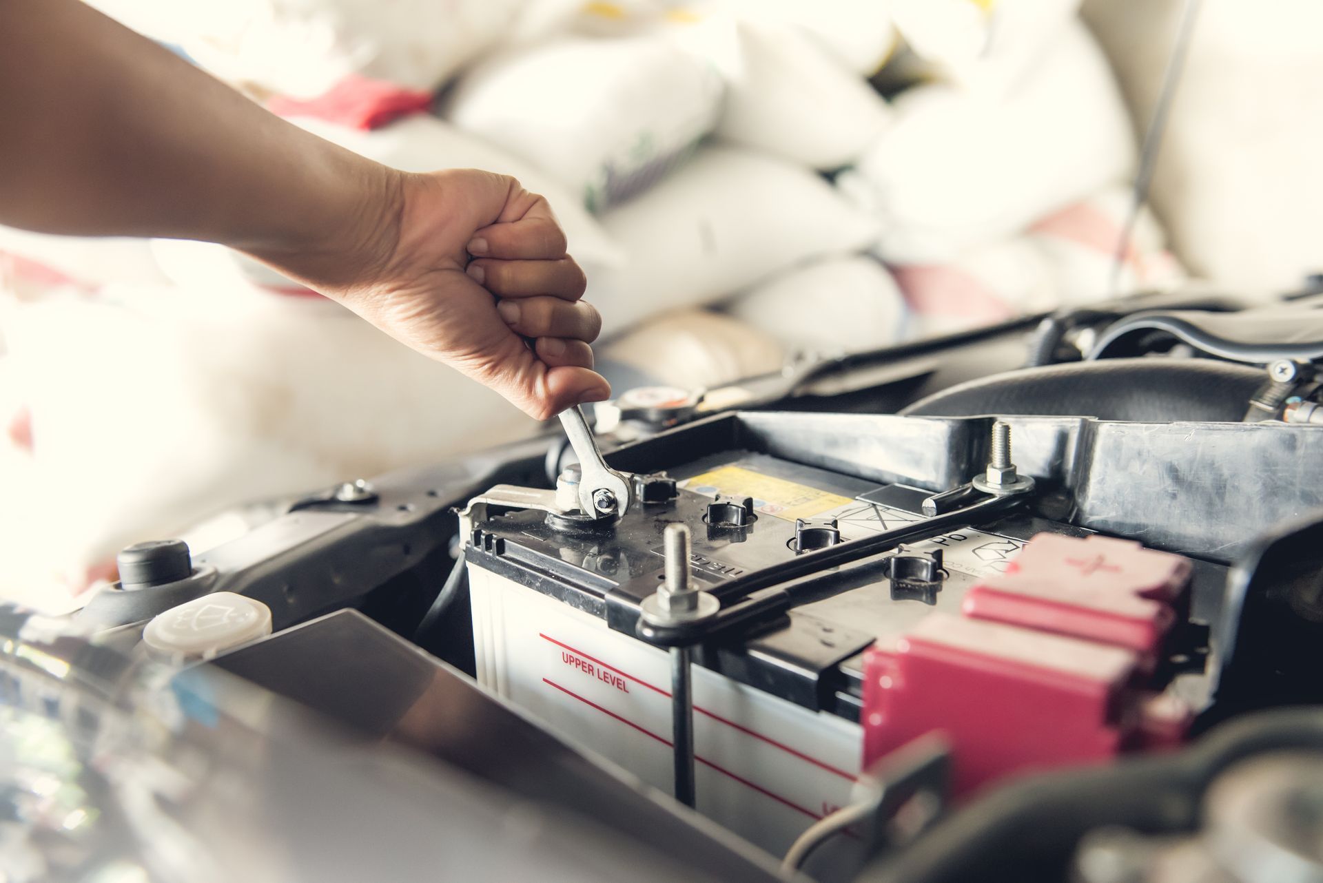 A person is fixing a car battery with a wrench.