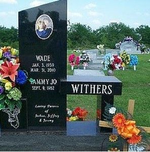 Black granite gravestone with flowers in a cemetery, engraved with names Wade, Tammy Jo, and Withers.