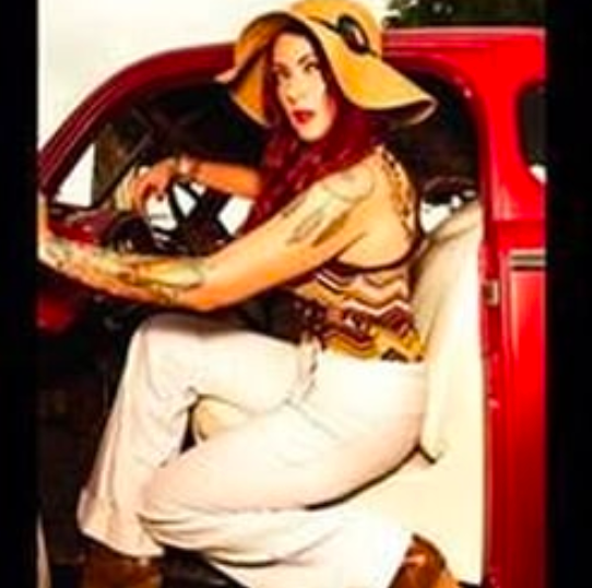 a woman in a hat is sitting in the driver 's seat of a red truck .