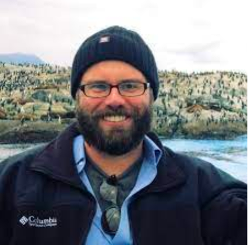 a man with a beard and glasses is wearing a beanie and a jacket .