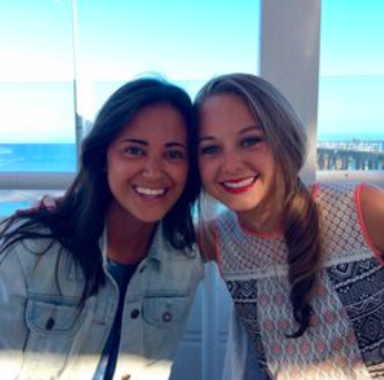 two women posing for a picture with the ocean in the background