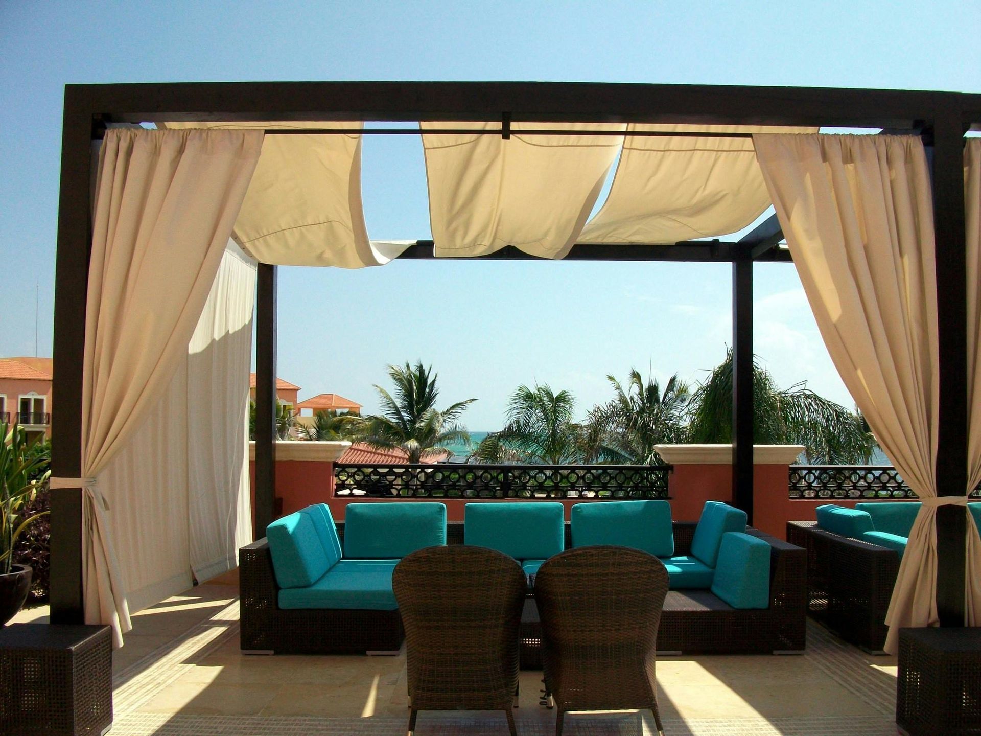A pergola with a couch and chairs underneath it