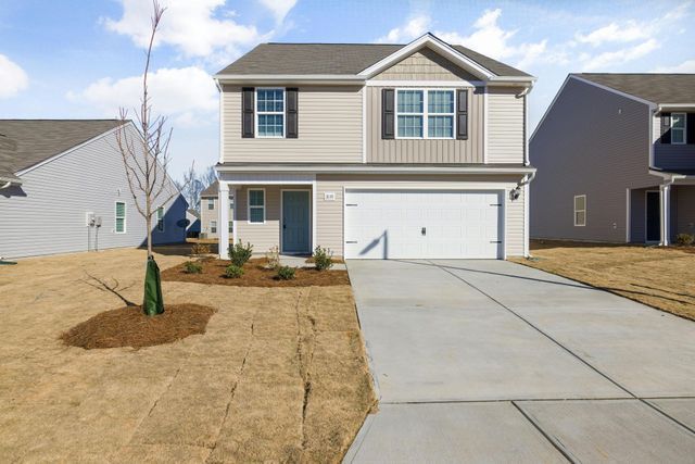 Two-story beige house with white garage and concrete driveway in a suburban neighborhood