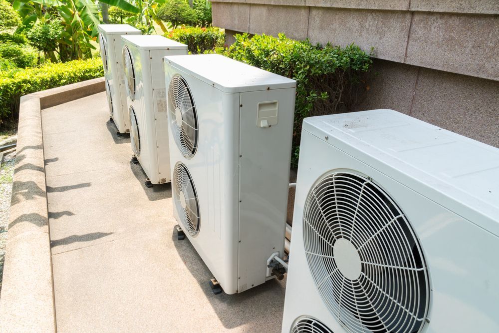 Row of Outdoor HVAC Units Beside a Building Wall on A Concrete Walkway — Alpine Refrigeration & Air Conditioning Pty Ltd in Wollongong, NSW