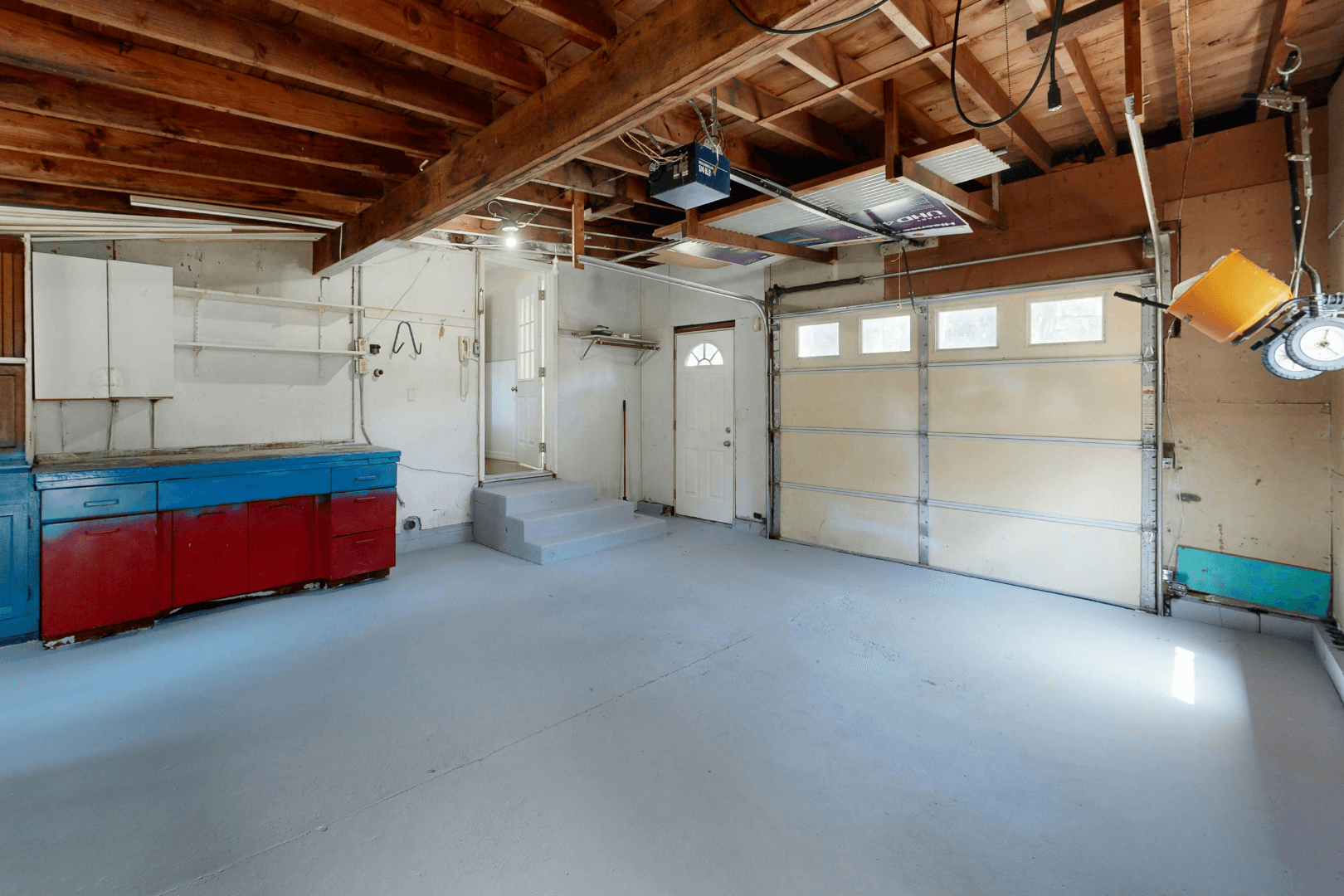 New blue house with a concrete driveway under construction, surrounded by dirt.