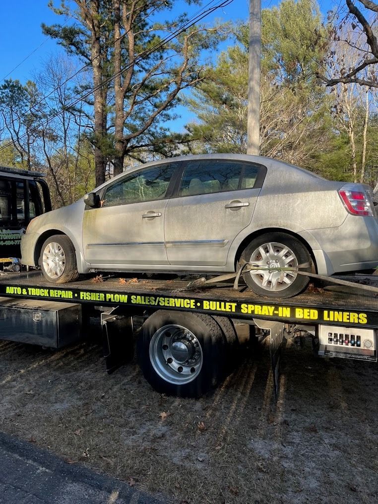 A silver car is sitting on top of a tow truck.