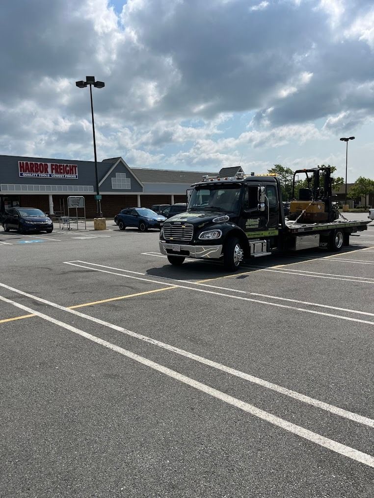A tow truck is parked in a parking lot in front of a store.