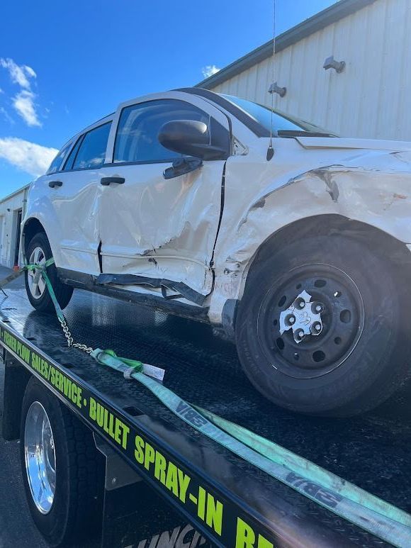 A white car is sitting on top of a tow truck.