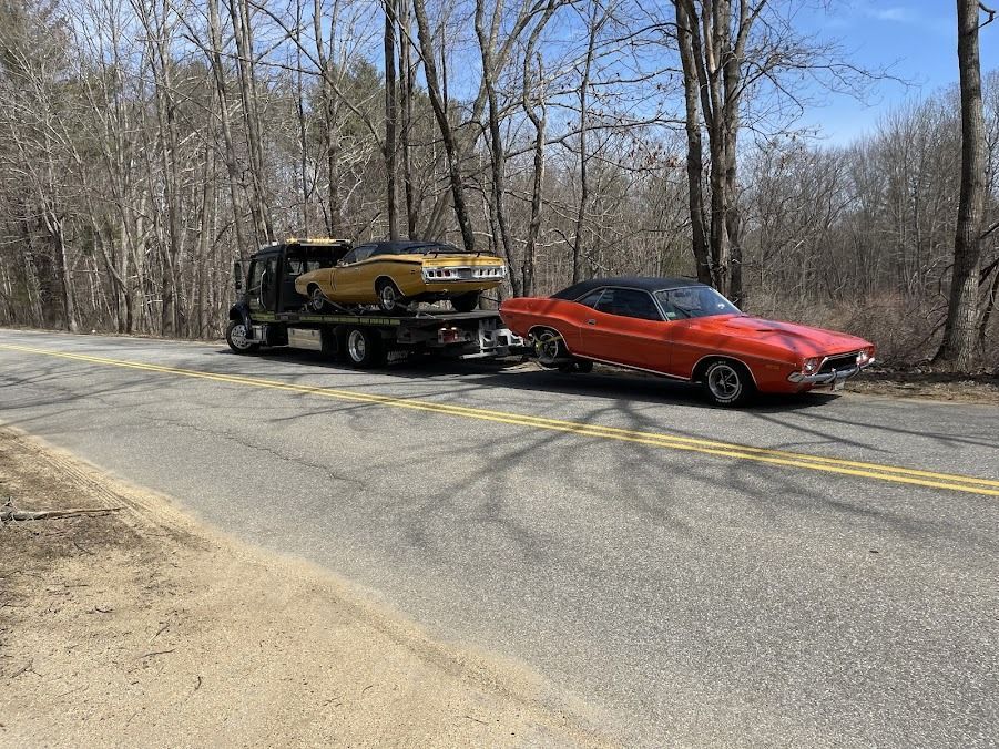 A yellow car is being towed by a red car on a tow truck.