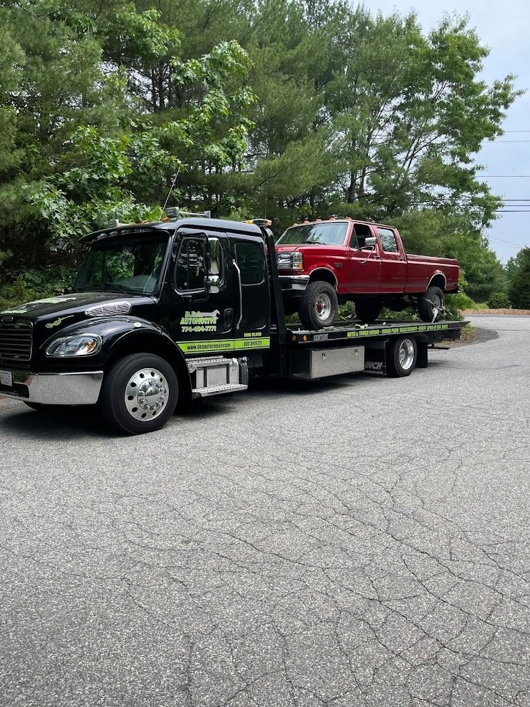 A red truck is being towed by a tow truck.