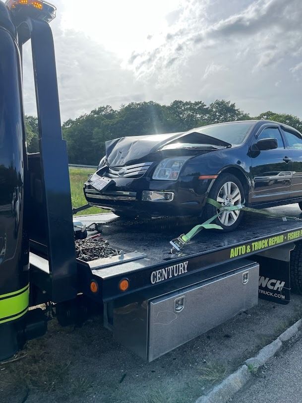 A black car is sitting on top of a tow truck.