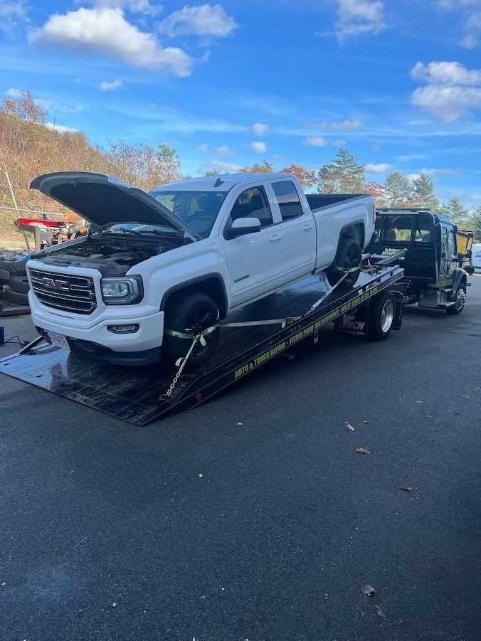 A white truck with its hood up is being towed by a tow truck.