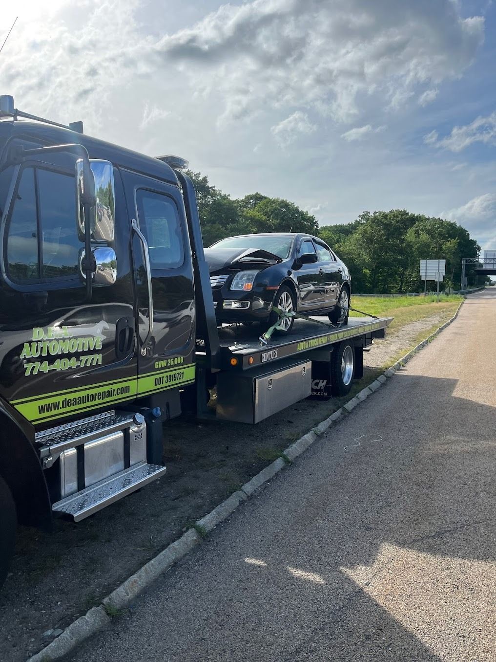 A tow truck with a car on the back is parked on the side of the road.