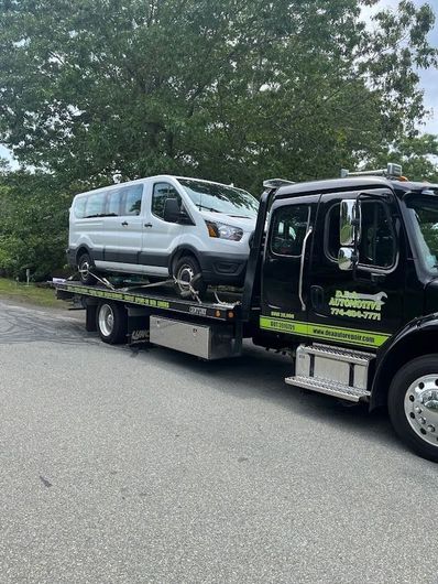 A white van is being towed by a tow truck.