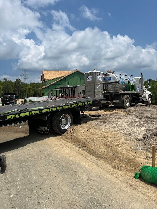 A tow truck is parked in front of a house under construction.