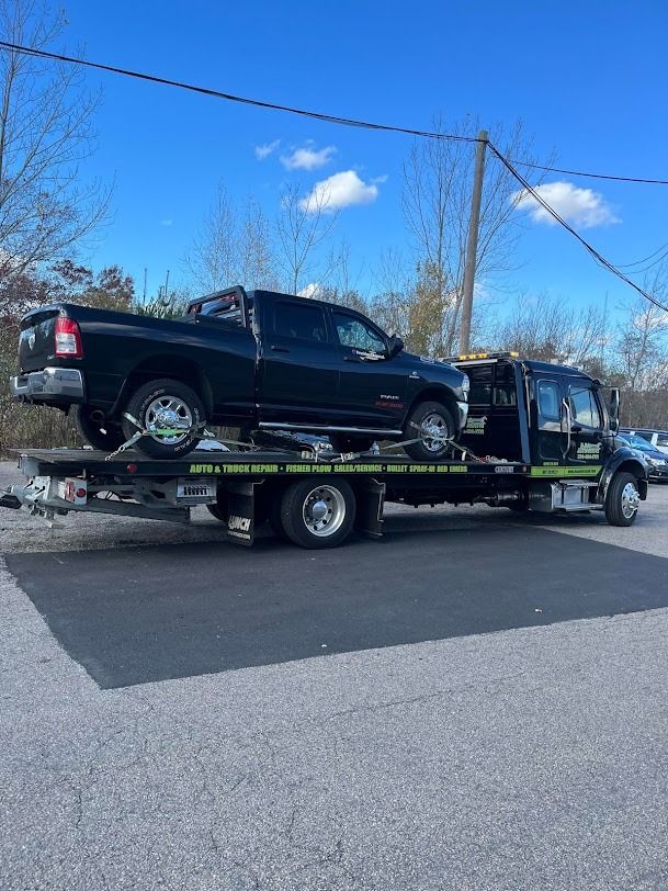 A black truck is being towed by a tow truck.