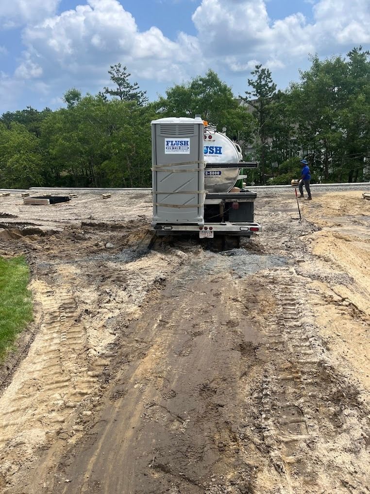 A portable toilet is sitting in the middle of a dirt road.