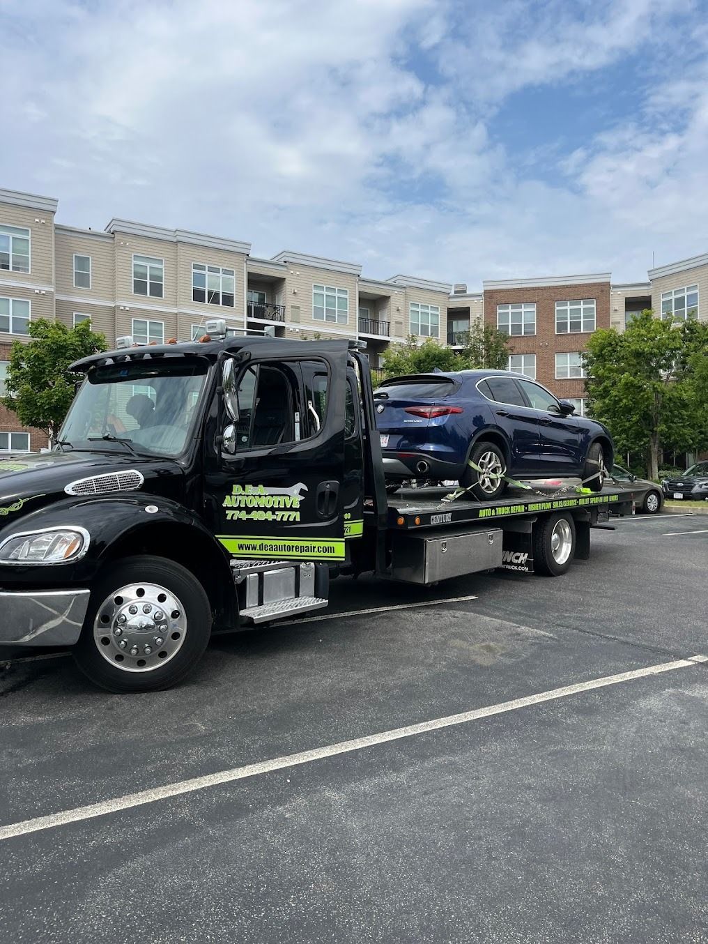 A tow truck is towing a car in a parking lot.