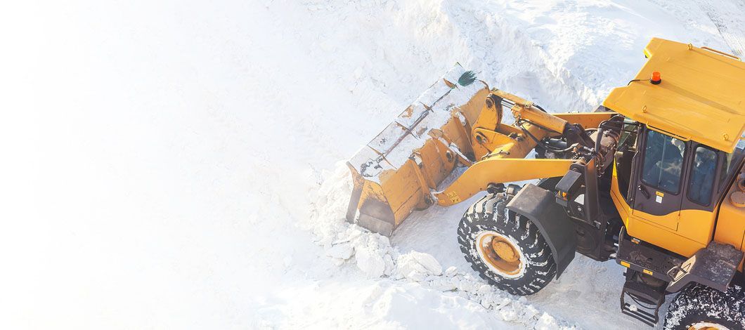 A yellow snow plow is clearing snow from a road.