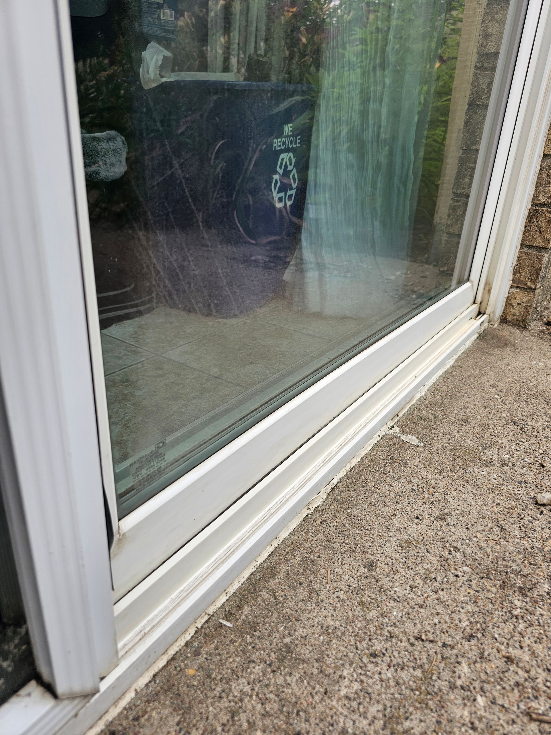 White sliding glass door frame on a concrete patio.
