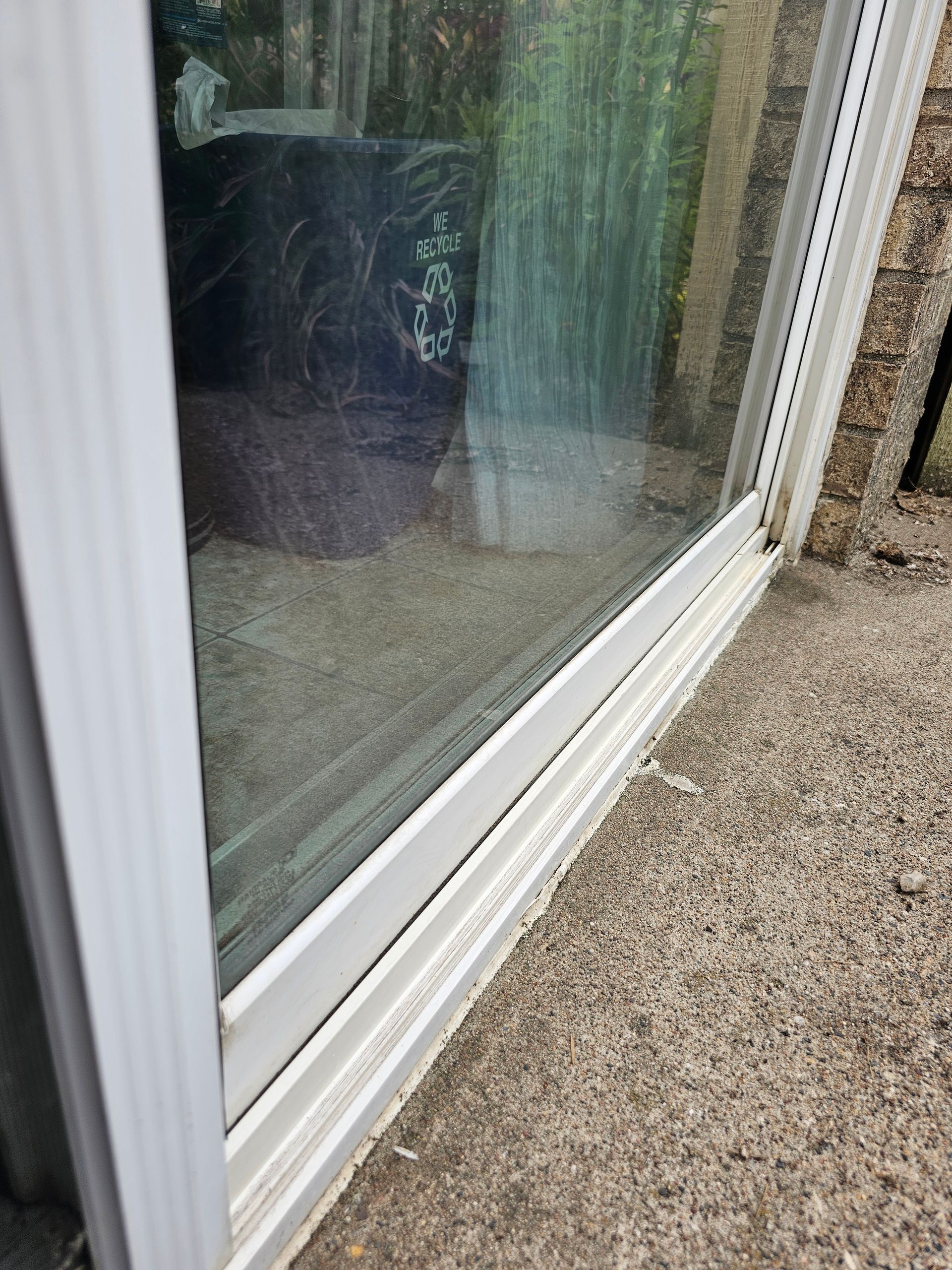 Close-up of a white-framed window on a concrete surface. The window is partially covered, and details inside are slightly visible.