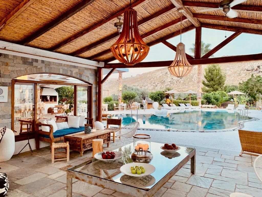 Poolside patio with wicker seating, low table, and a swimming pool under a thatched roof