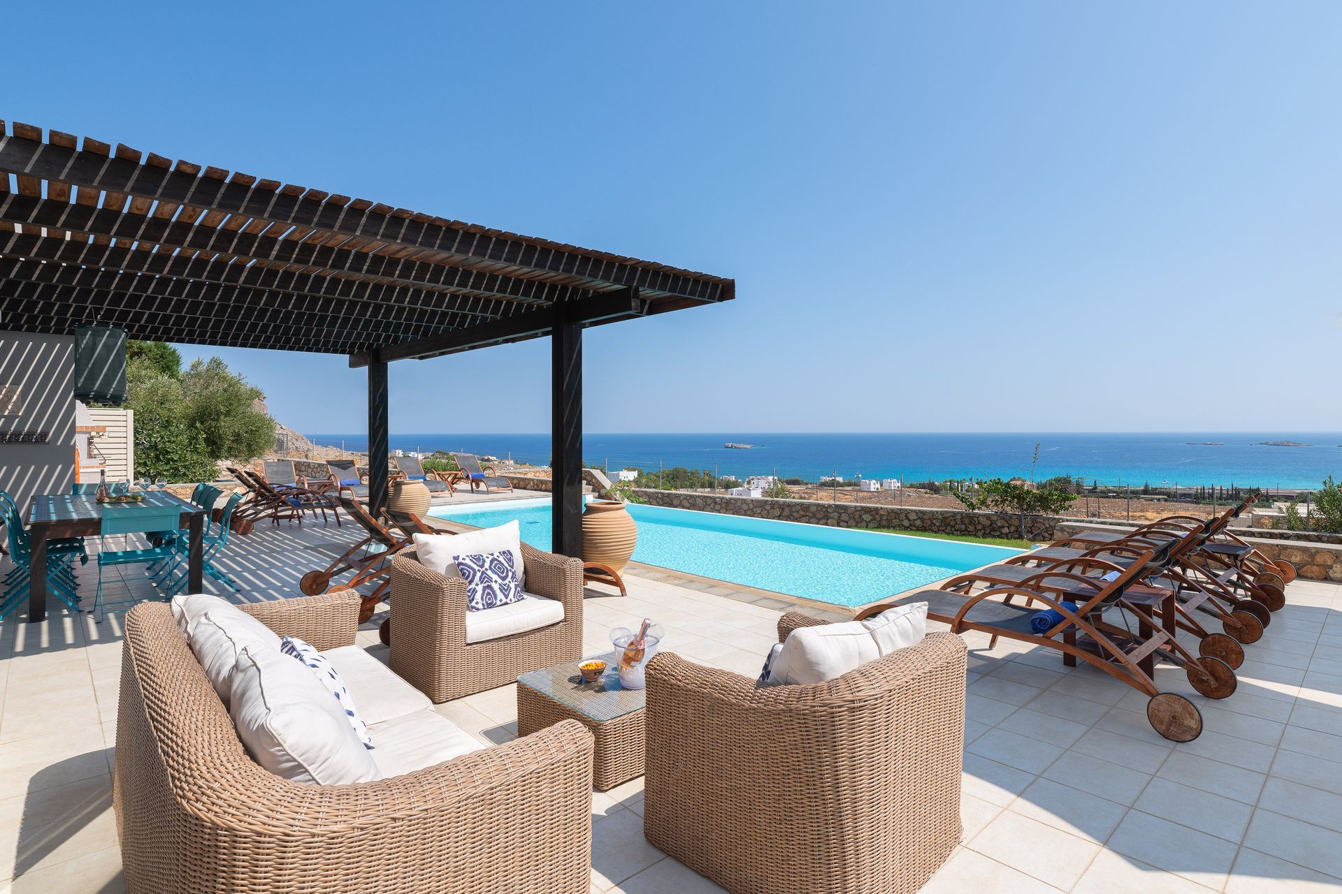 Oceanfront patio with wicker lounge chairs, shaded seating, and a pool overlooking the sea