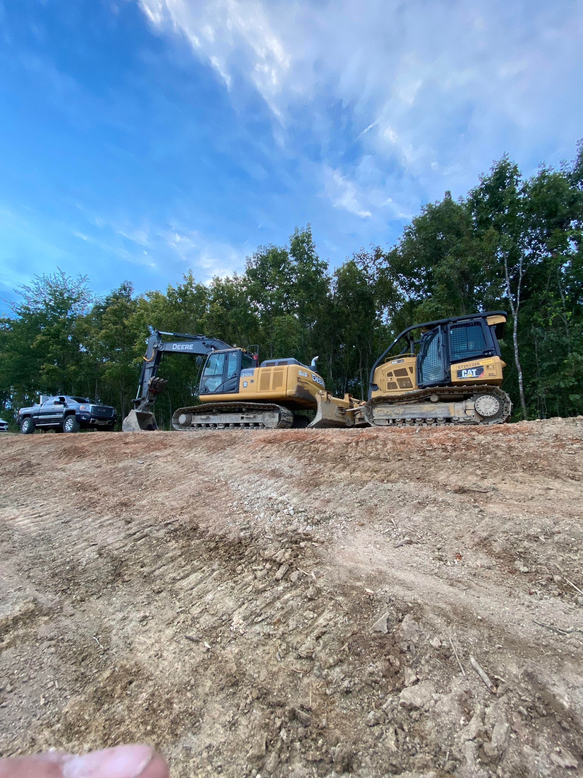 Two bulldozers are sitting on top of a dirt hill.