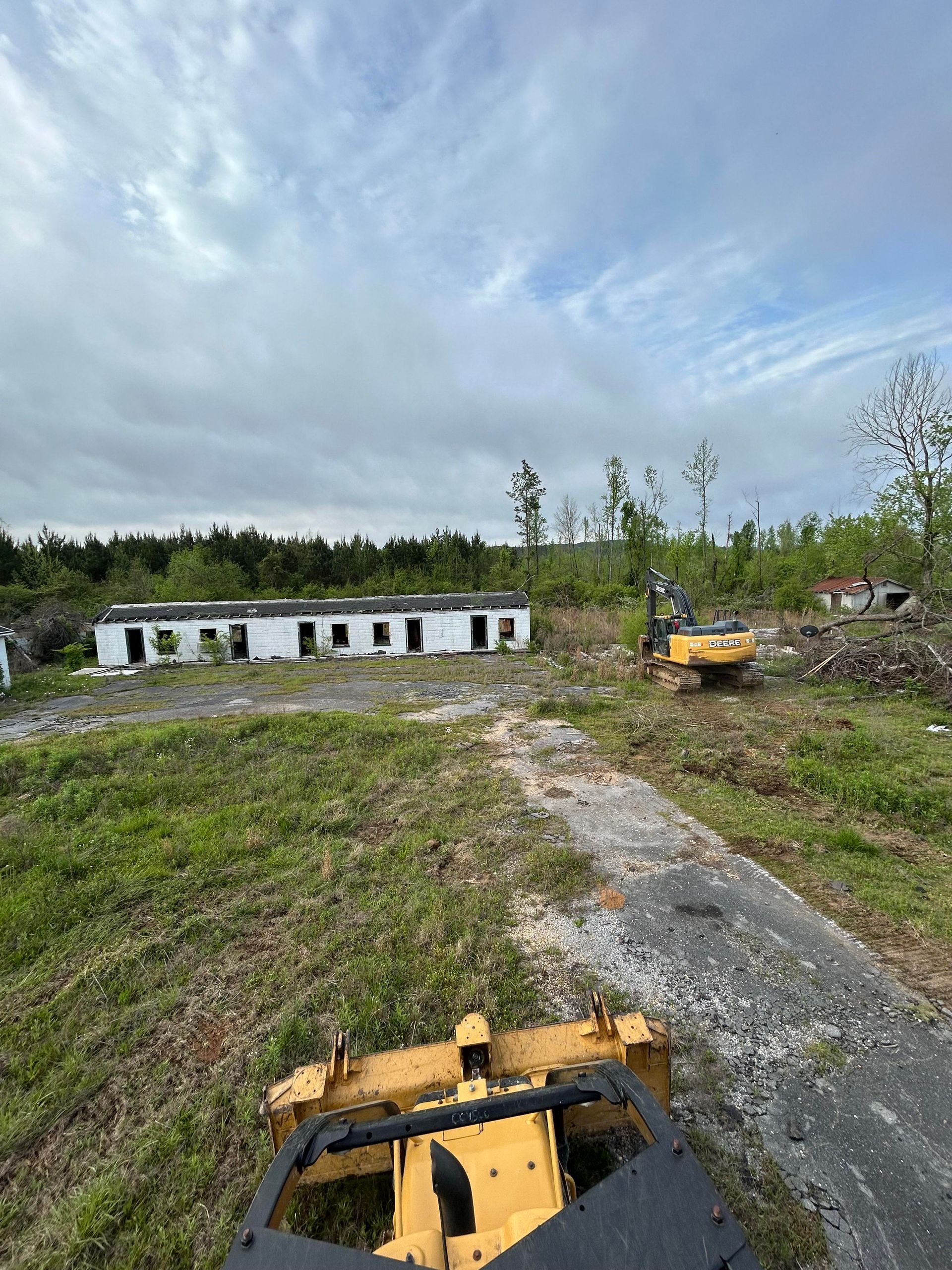 A yellow bulldozer is parked on the side of a dirt road in a field.