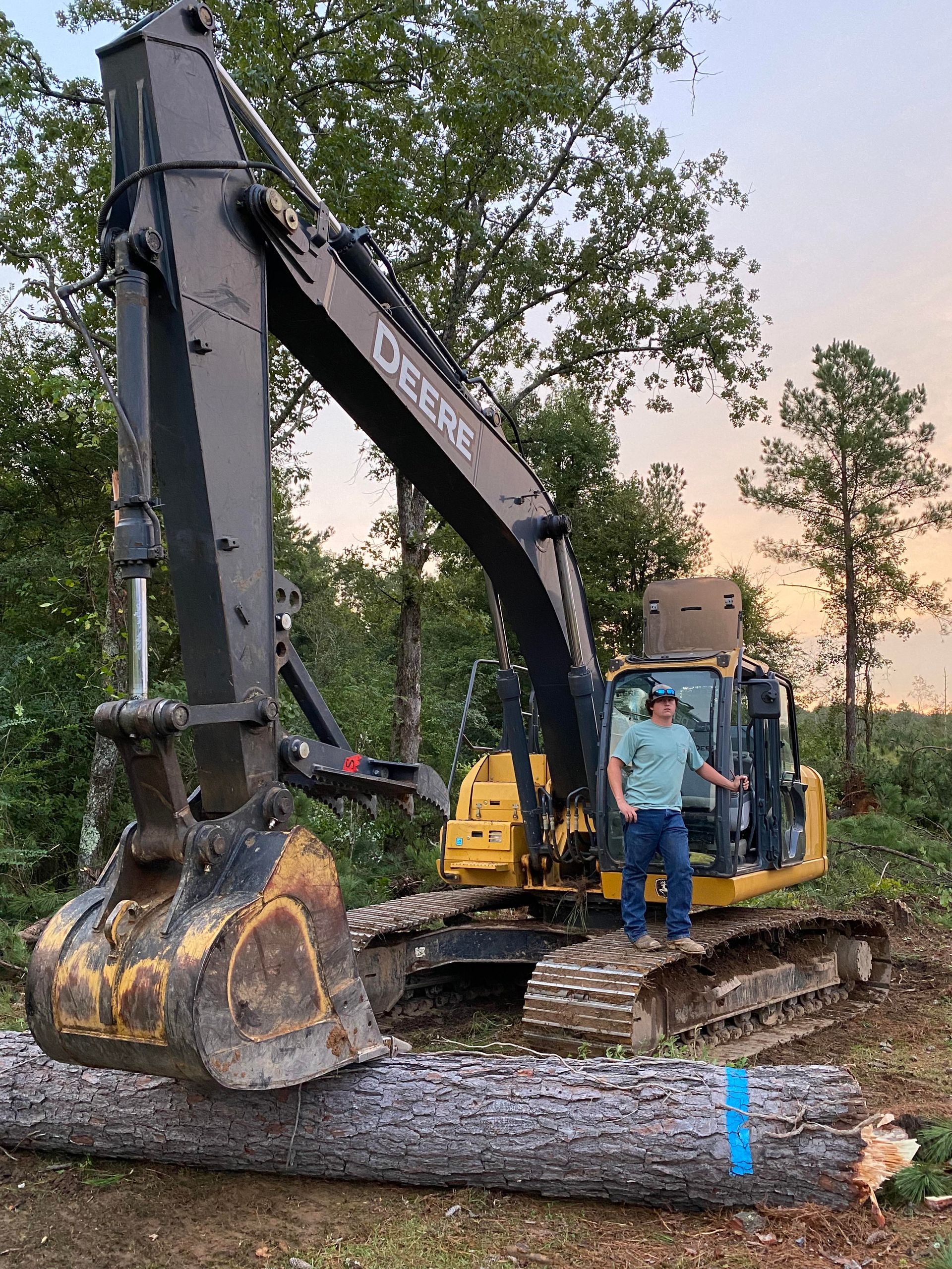 A man is standing in front of a large excavator.