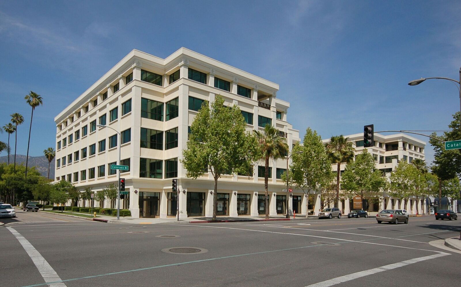Building exterior with a grassy lawn and trees. Beige and black facade, sunny day.