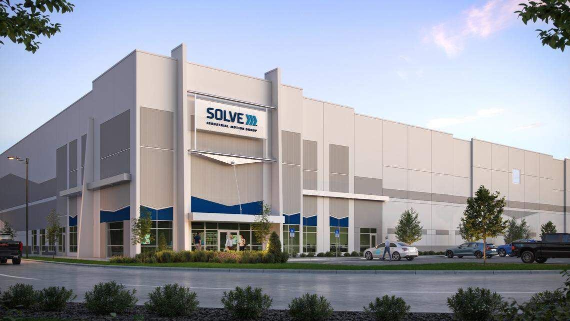 Warehouse exterior with loading docks, semi-trucks, and a black van on a wet, overcast day.