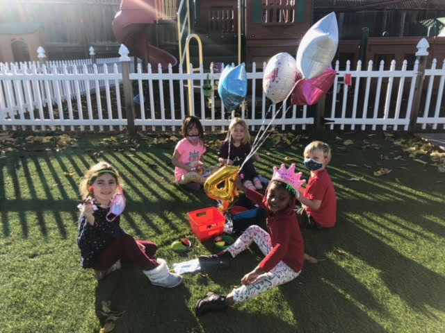 children with balloons outside for party