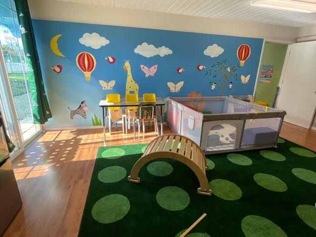 Inside view of Alpha Kids Academy play area with rug and playpen