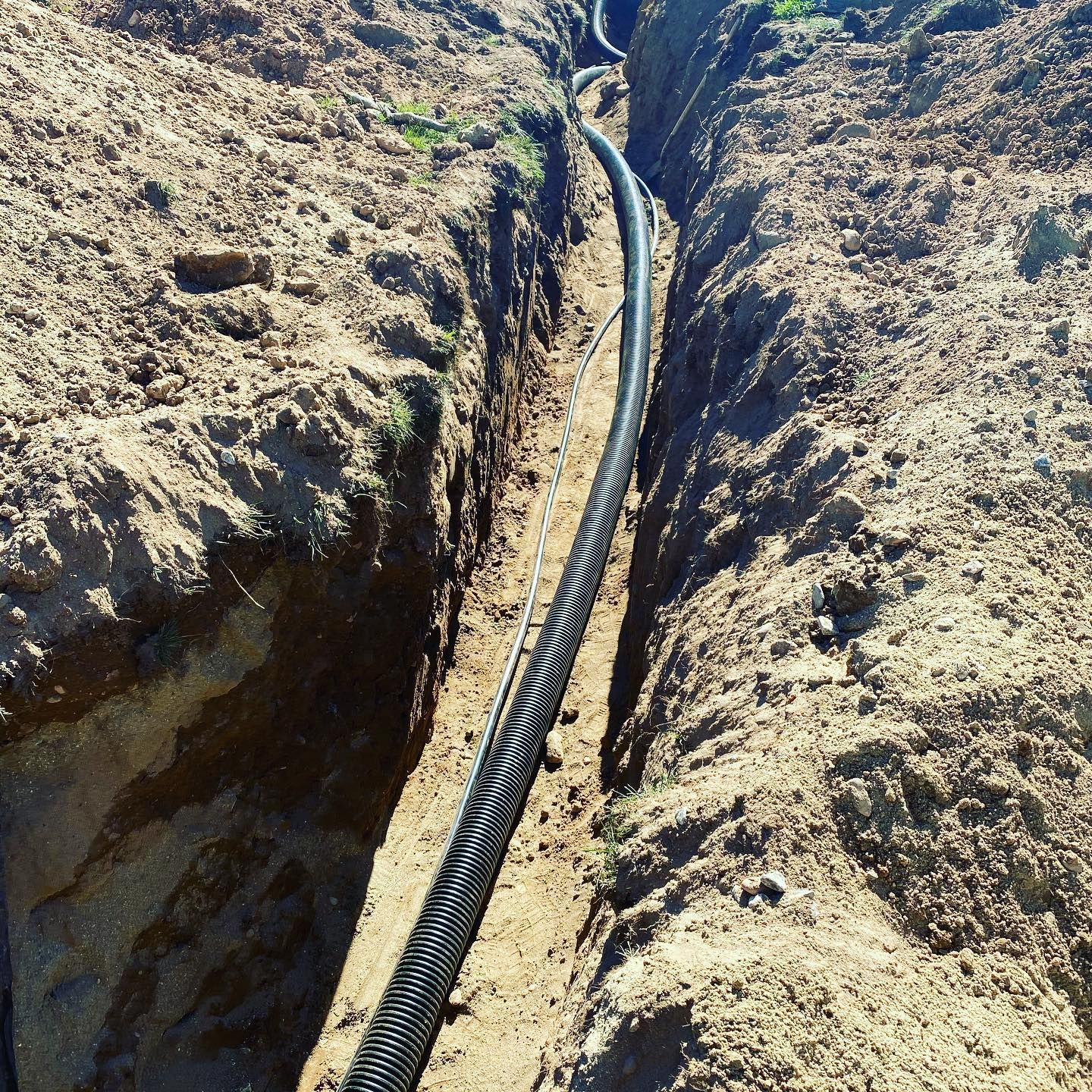 A hose is laying in the dirt in a trench