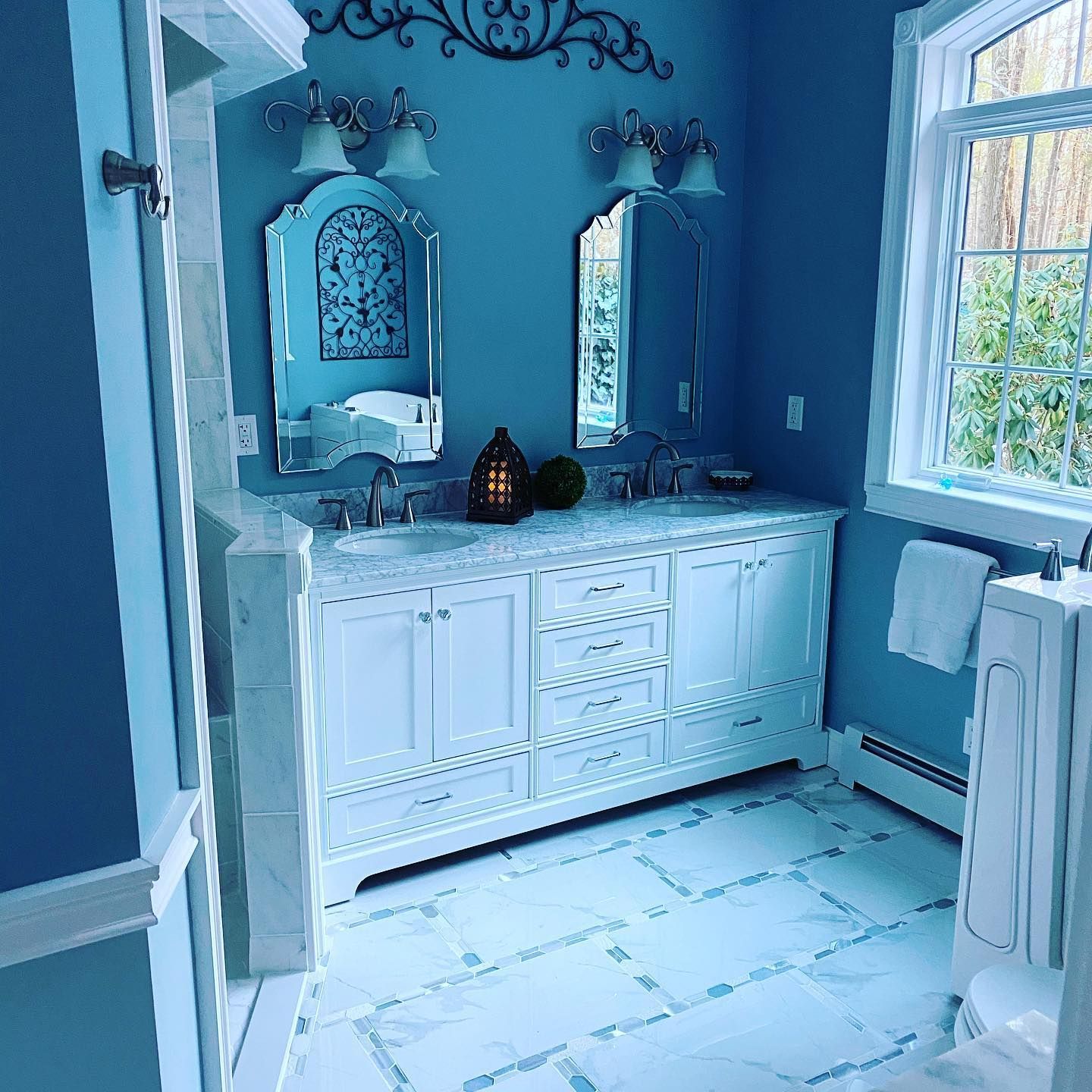 A bathroom with blue walls and white cabinets