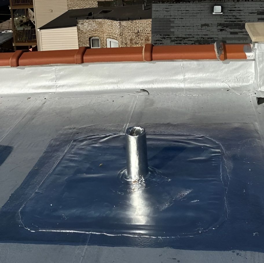 Flat roof with a silver pipe, sealed with a silver square, and brown pipes above.