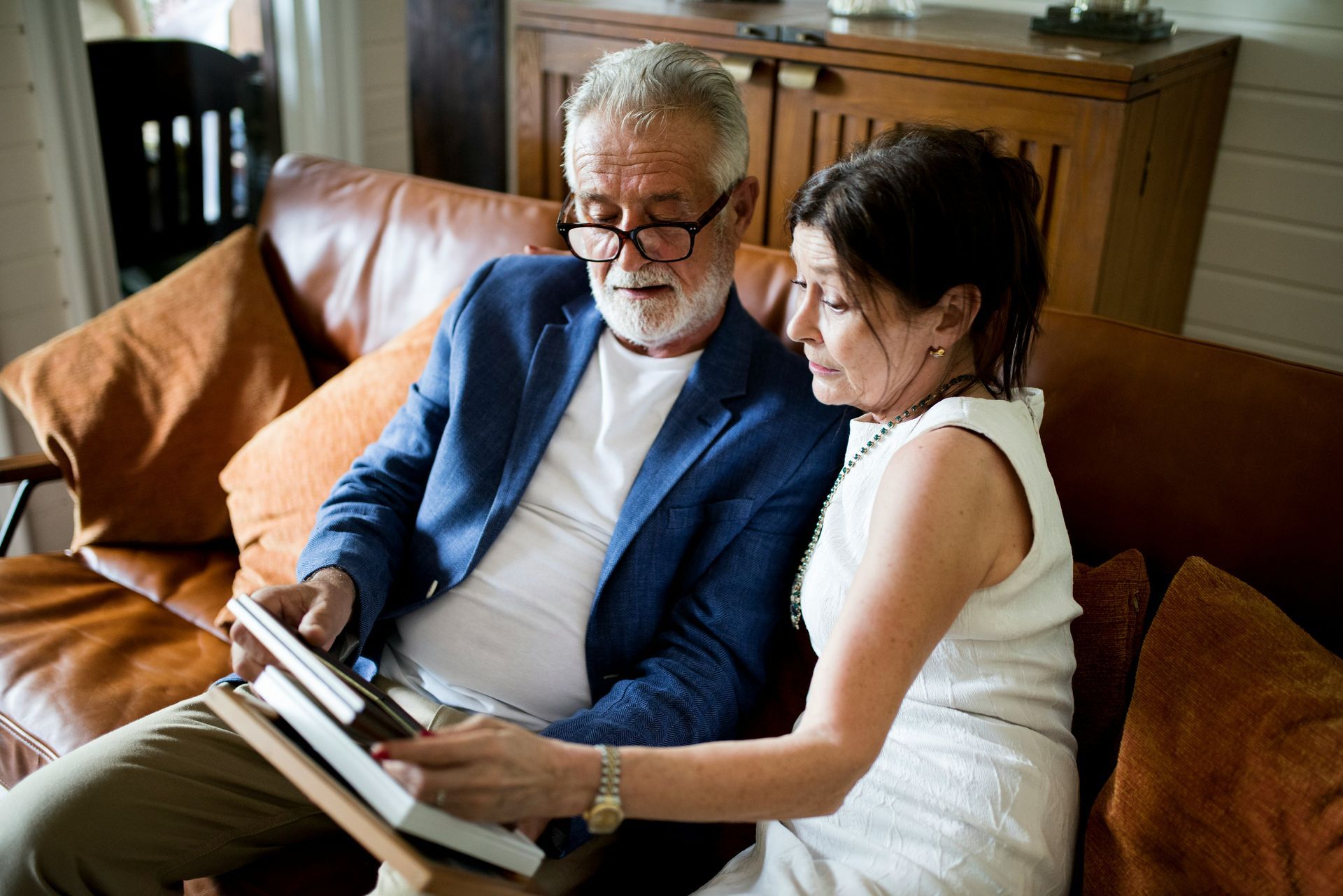 A man and a woman are sitting on a couch reading books.