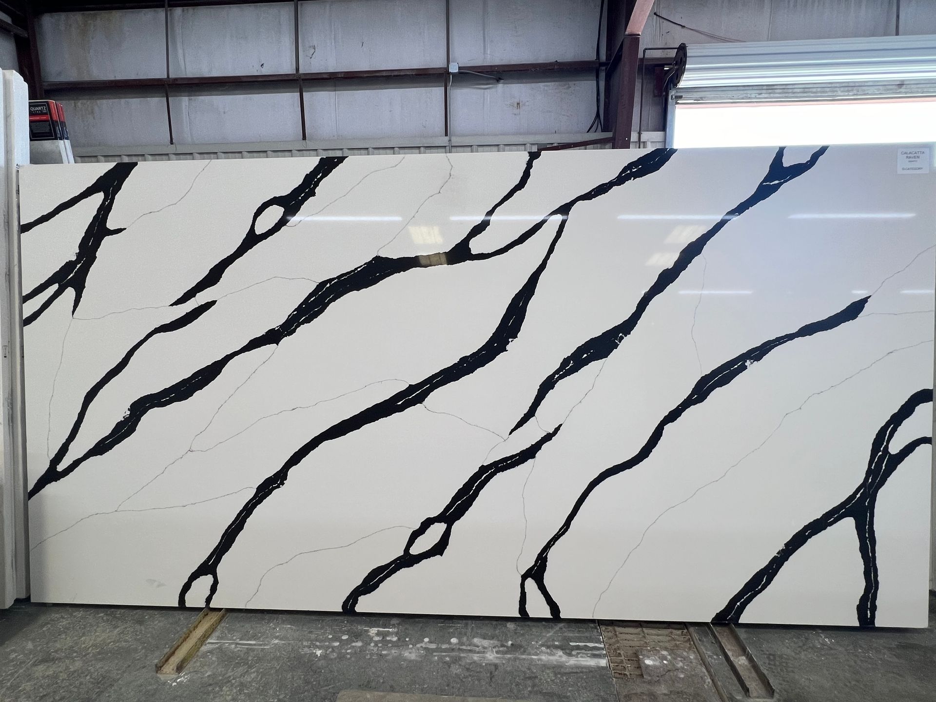 A large white and black marble slab is sitting in a warehouse.