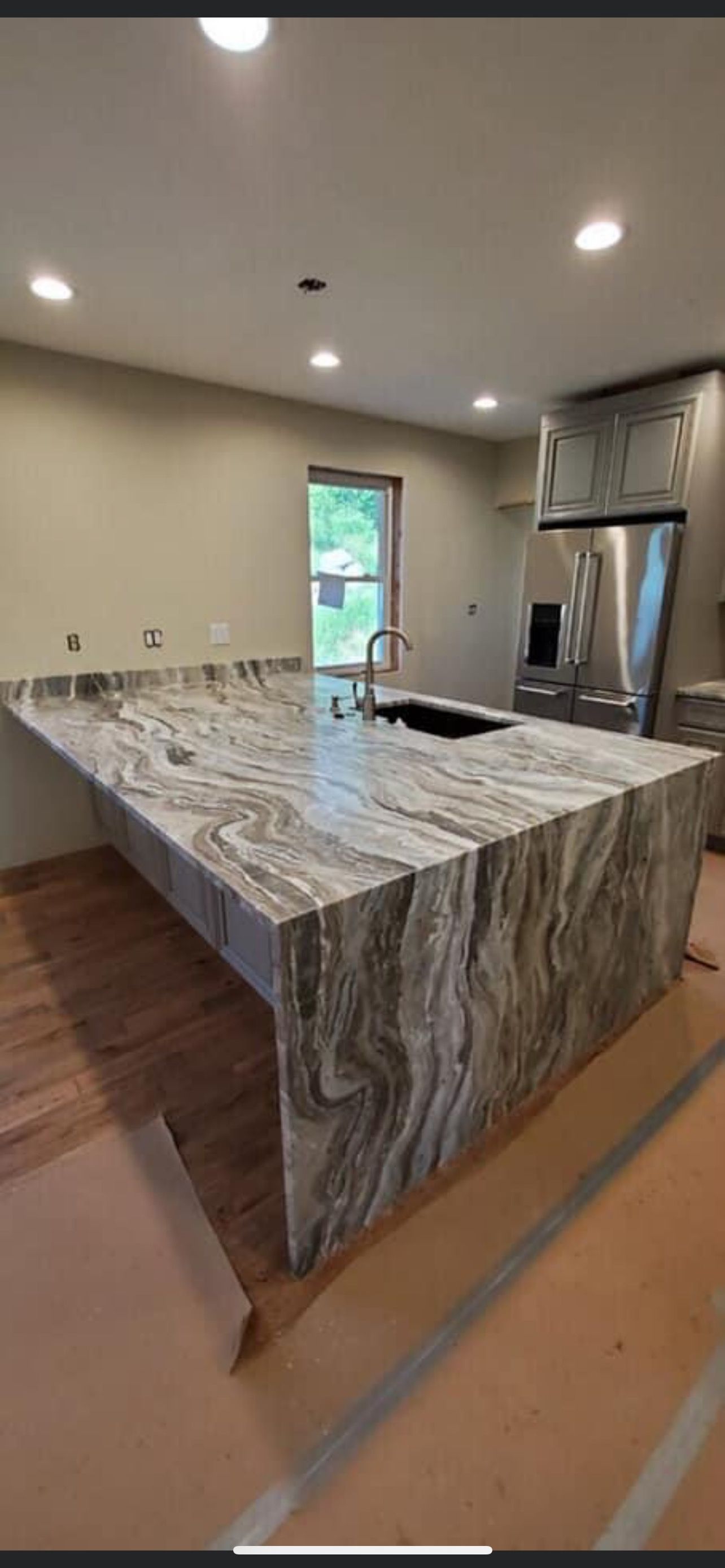 A kitchen with a large granite counter top and stainless steel appliances.
