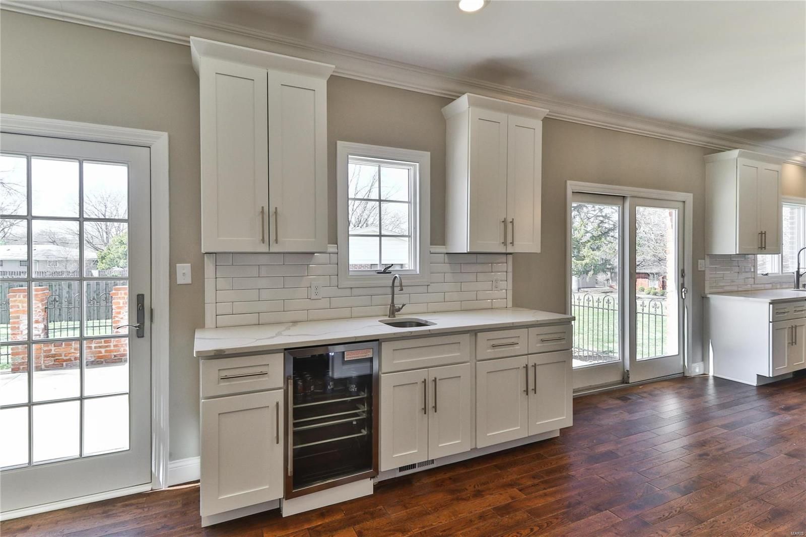 A kitchen with white cabinets , stainless steel appliances , and hardwood floors.